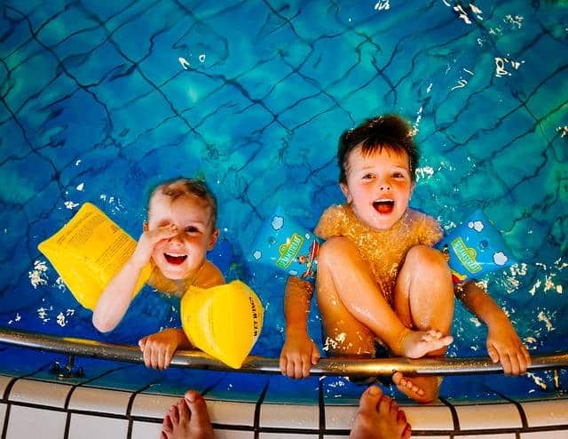Deux enfants assis au bord d'une piscine.