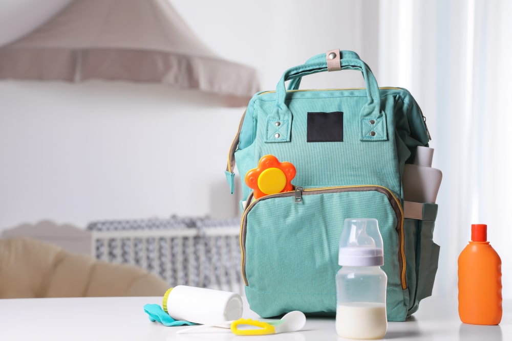 Un sac à langer avec des biberons et d'autres articles posés sur une table. On peut mettre dedans tout le nécessaire pour bébé.