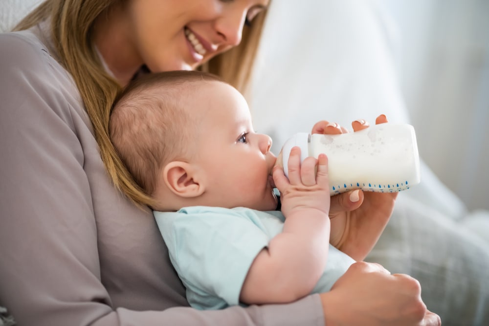 Une femme utilisant des techniques pour nourrir son bébé avec du lait au biberon pendant l'allaitement.