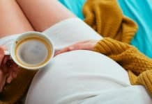 Une femme enceinte tenant une tasse de café.