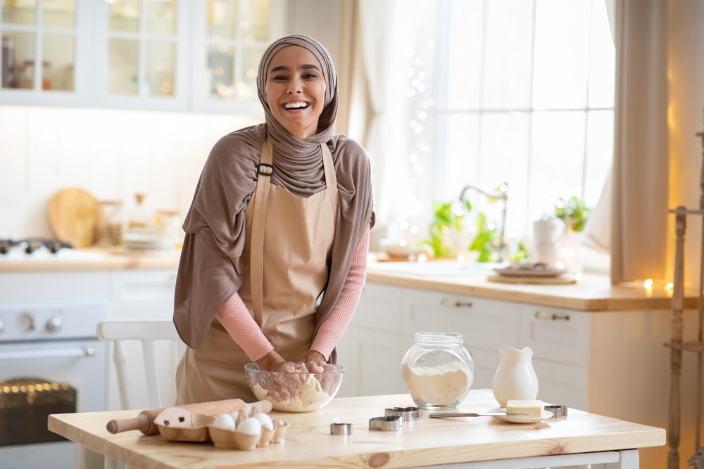 Une femme musulmane portant un hijab préparant de la nourriture dans la cuisine pendant le Ramadan.