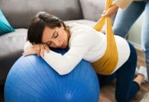 Une femme est allongée sur un ballon d'exercice bleu en harmonie pendant la grossesse.