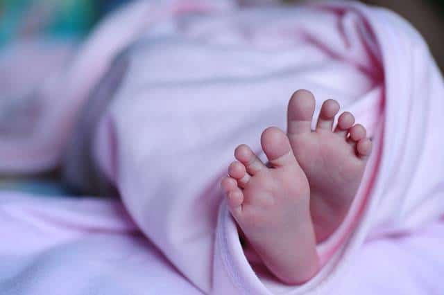 Pieds de bébé sortant d'une couverture rose Brouillon.