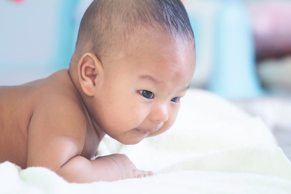 Bébé allongé sur le ventre sur un matelas Topponcino, regardant sur le côté avec une expression curieuse.