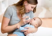 Femme nourrissant un bébé avec un biberon en biberons en verre.